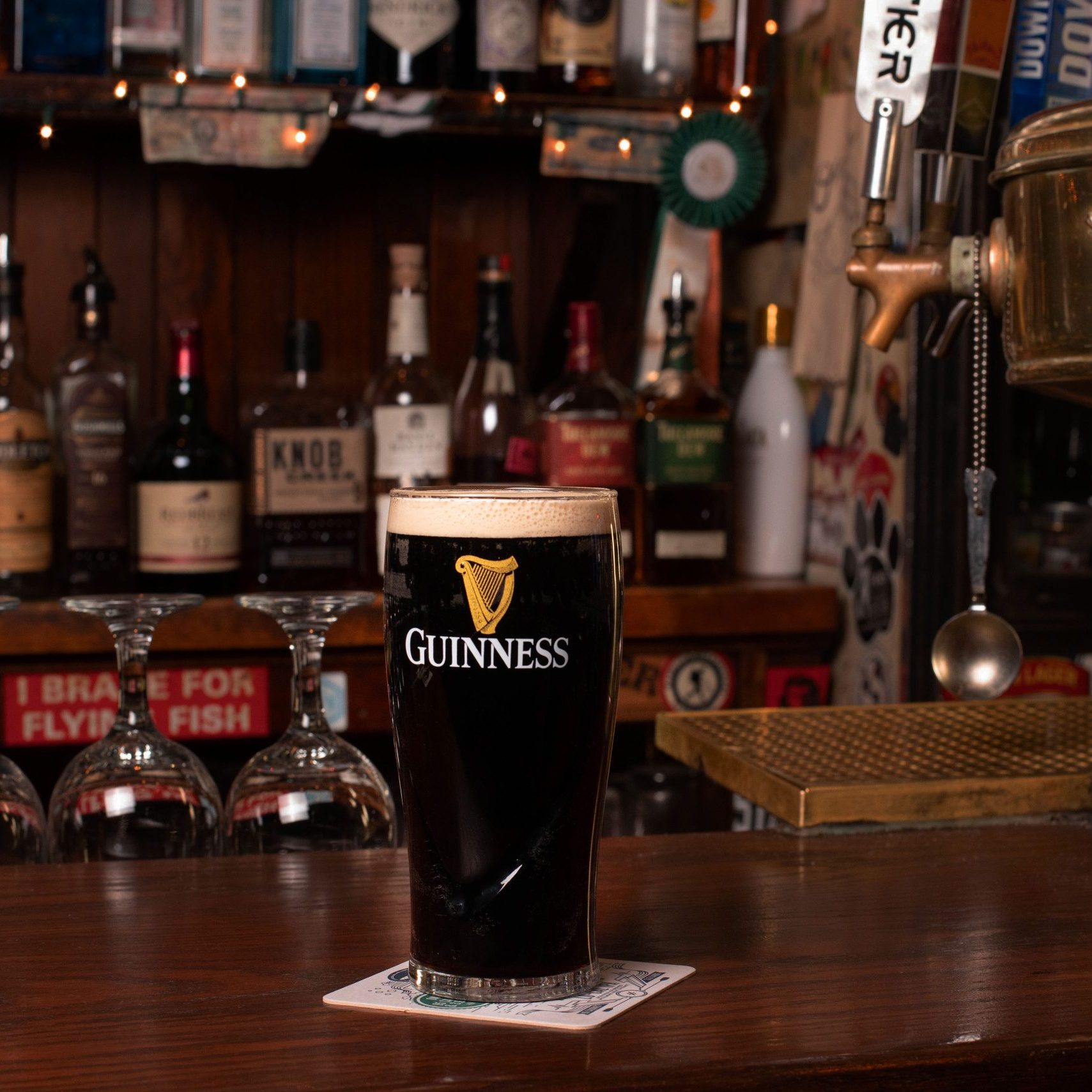 A glass of guinness sitting on a bar.